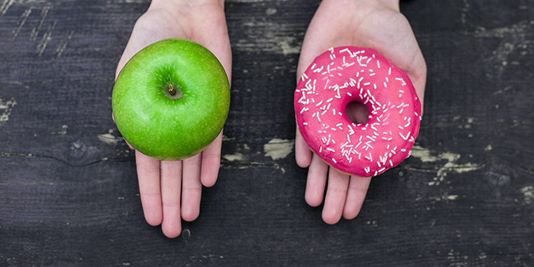 green apple and pink doughnut held in palms