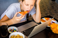 poor lifestyle represented by eating junk food over a laptop